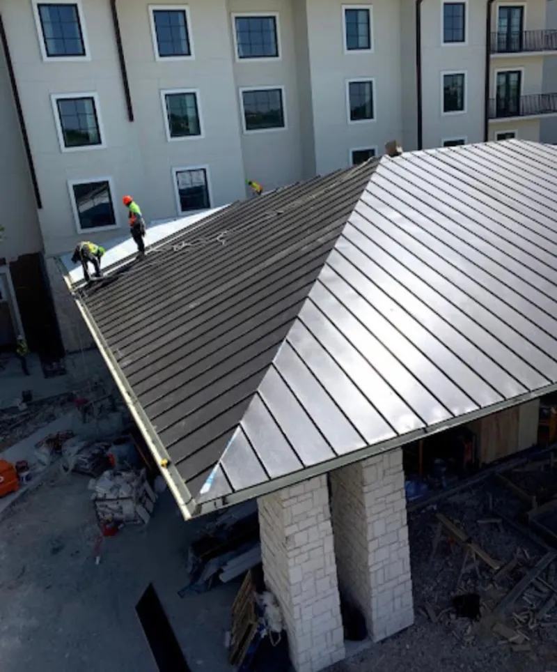 Crew installing standing seam metal roof panels on a commercial project in Slinger